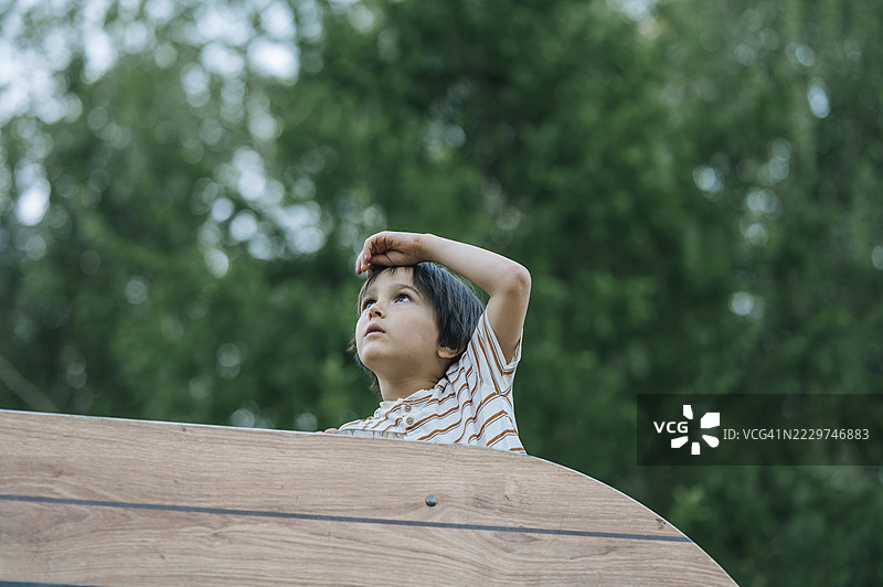 穿着条纹衬衫的男孩在夏天的游乐场望向远方图片素材