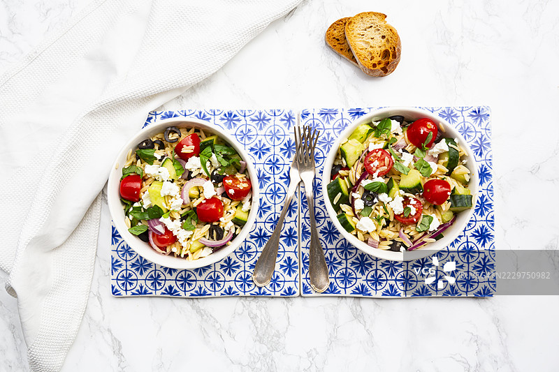 地中海风味的意大利米沙拉，配有羊奶酪、橄榄和烤面包，摆放在大理石表面上图片素材