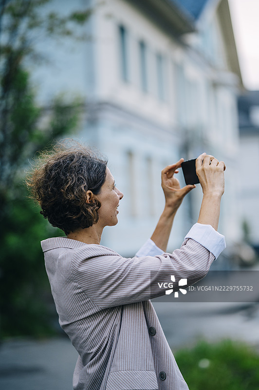 女性在户外用智能手机拍摄城市风景图片素材