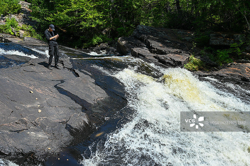 少年男孩在拍摄瀑布的照片图片素材