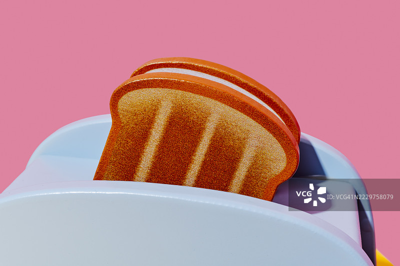 粉色背景上的玩具烤面包机和烤面包图片素材