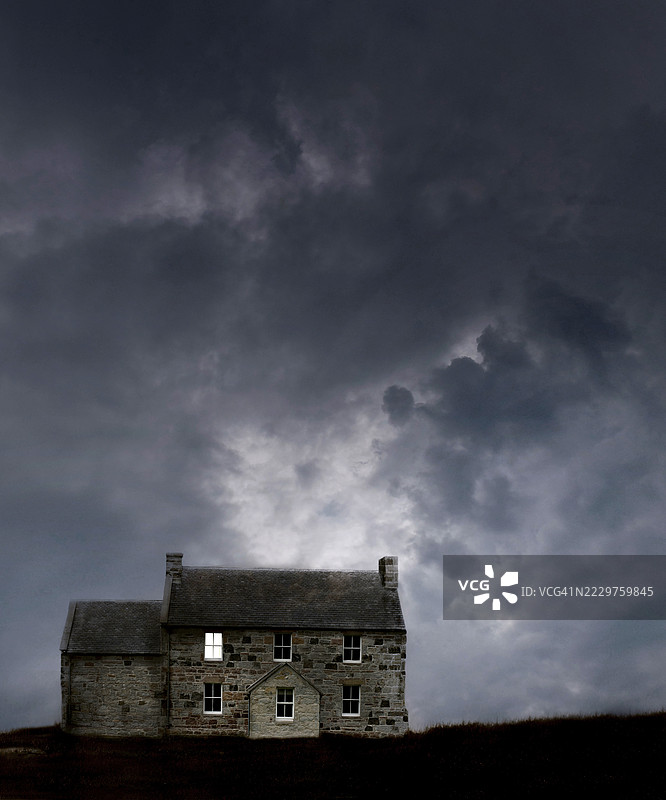暴风雨天空下的孤立石屋在傍晚时分图片素材