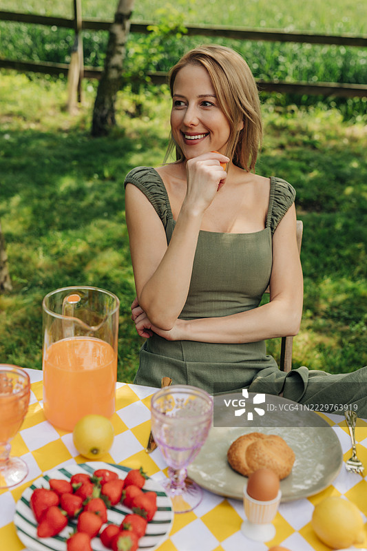 微笑的女性在户外桌子上享受健康的夏季早餐图片素材