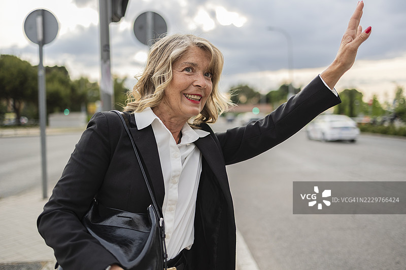 早晨，女商人在城市街道上招手叫出租车图片素材