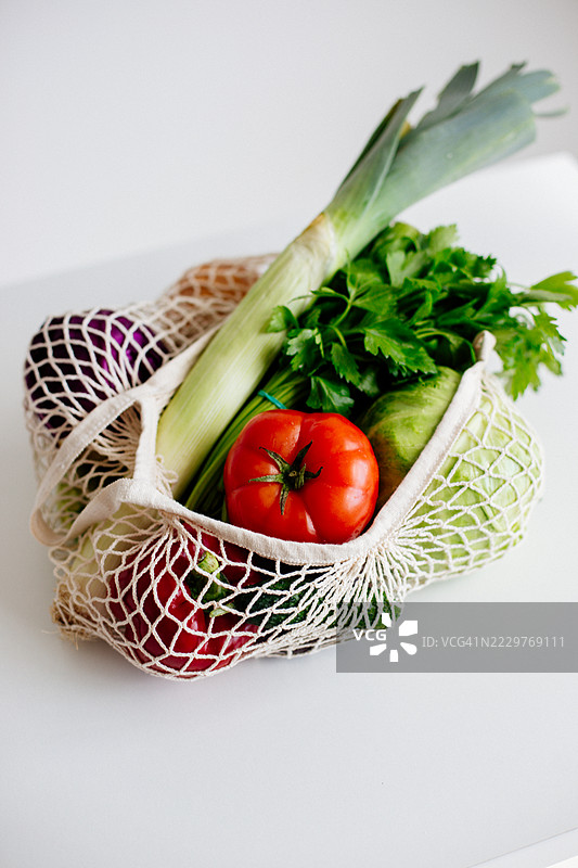 新鲜有机蔬菜放在白色表面的可重复使用网袋中图片素材