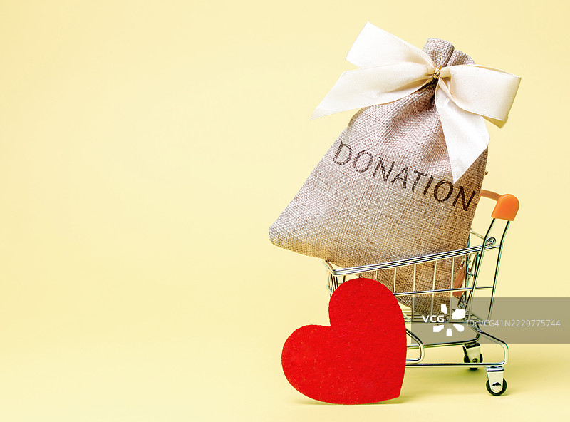 黄色背景上的购物车内有捐赠袋和心形图案，乌克兰图片素材