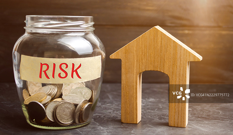标有“风险”的硬币罐旁边是一个象征金融不确定性的木屋模型，乌克兰图片素材