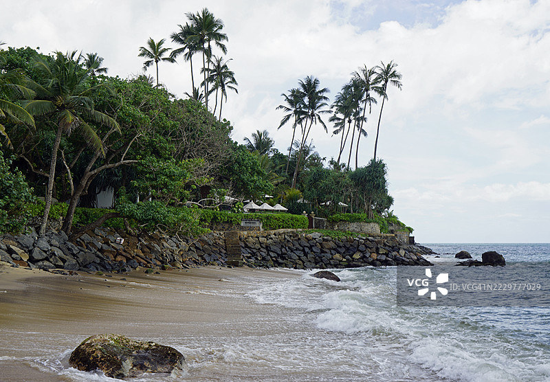 斯里兰卡的热带海滩，棕榈树与岩石海岸线图片素材