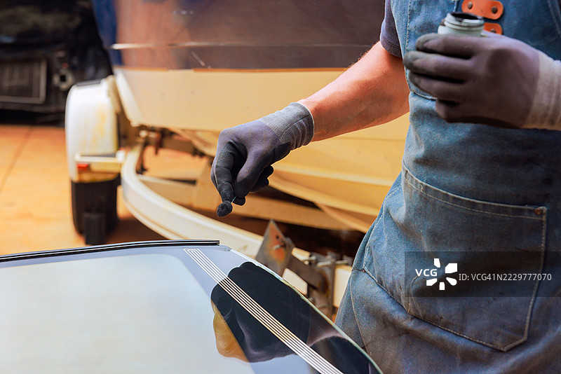 工人在汽车细节处理过程中为挡风玻璃涂抹密封剂图片素材