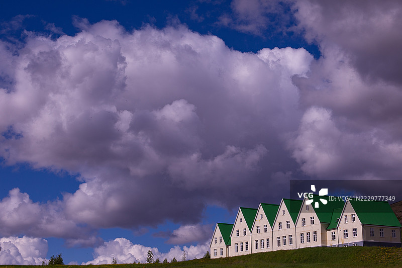 一排绿色屋顶的房屋在戏剧性的多云天空下，冰岛图片素材