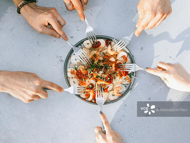手伸向共享的虾沙拉盘，乌萨克，土耳其图片素材