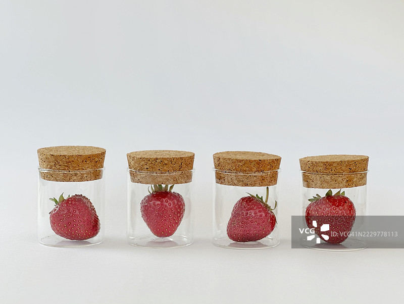 四个装在玻璃罐中的草莓，带有软木塞，背景为白色，爱沙尼亚图片素材