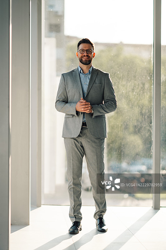 商人在现代办公大楼中微笑并摆姿势图片素材