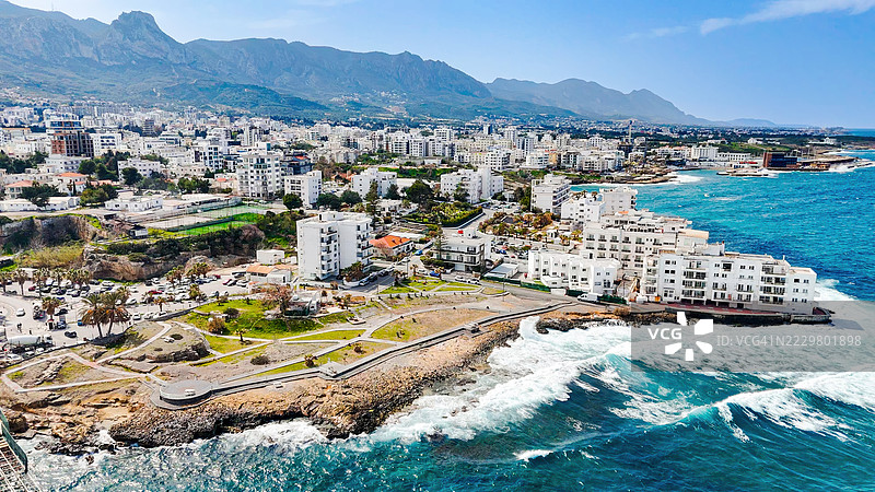 基尔尼亚海岸线的鸟瞰图，现代建筑与海滨长廊，北塞浦路斯城市风景，背景是山脉，旅行目的地和地中海生活方式概念图片素材