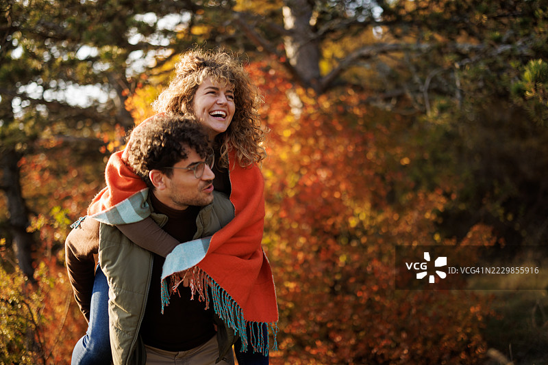 快乐的情侣在秋天的自然中享受背负骑行的乐趣图片素材