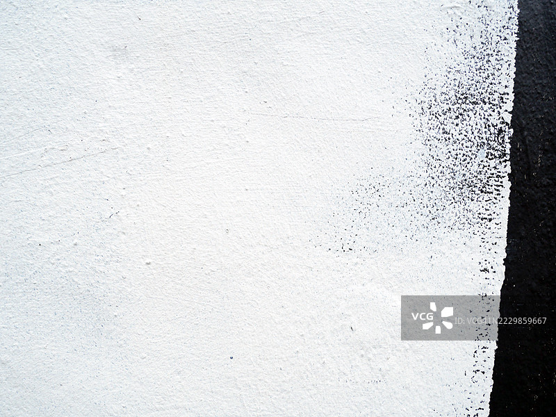 一层纹理白色涂料覆盖着黑色的混凝土墙。地点：伦敦，英格兰，英国。白天。自然色彩。图片素材