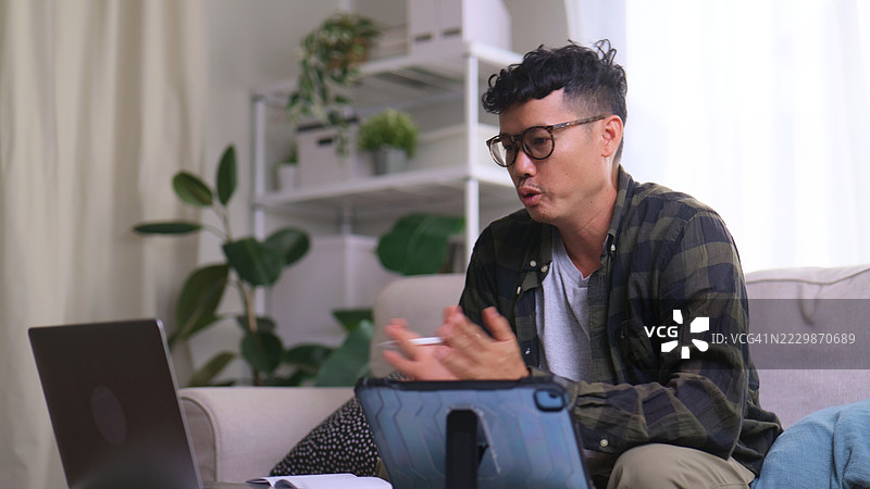 商务沟通 – 亚洲男性在平板电脑和笔记本电脑上进行视频会议。图片素材