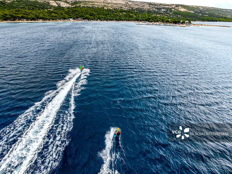 女性滑水者在水上被摩托艇牵引的动态镜头，背景是戏剧性的云彩图片素材