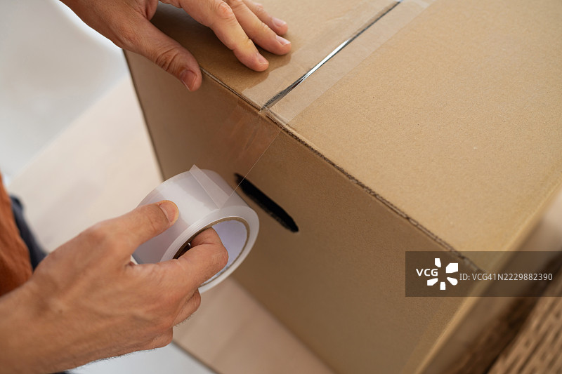 一个人在打包过程中用透明胶带封好一个纸板箱图片素材