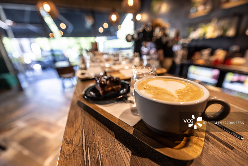 意大利小餐馆、咖啡馆或小酒馆吧台上，一杯卡布奇诺和甜点的广角镜头，背景模糊的室内环境。图片素材