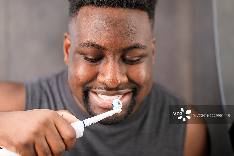 微笑的男子在浴室使用电动牙刷进行口腔卫生护理图片素材