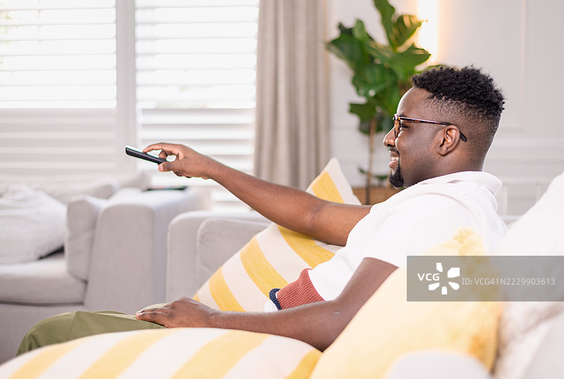 男人在现代舒适的客厅沙发上放松，看电视图片素材