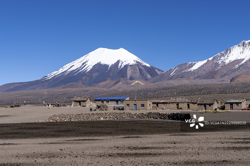 在玻利维亚奥鲁罗省库拉瓦拉德卡兰加斯的萨哈马国家公园，雪覆盖的帕里纳科塔火山前的房屋图片素材