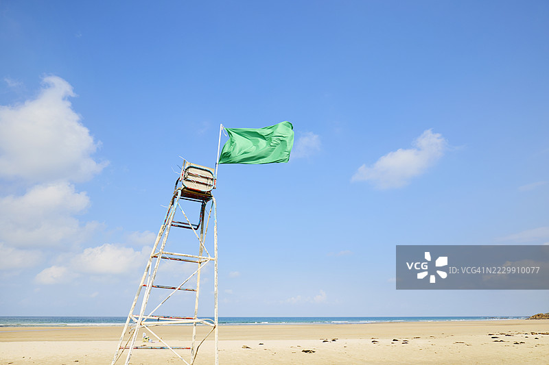 在蓝天背景下，救生椅上的绿色旗帜在风中飘扬图片素材