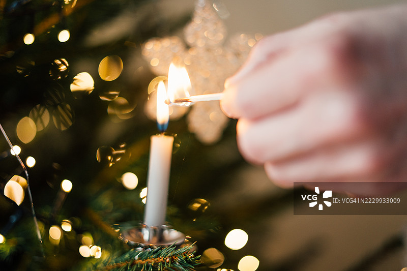 在圣诞树上点燃蜡烛。温馨的节日氛围图片素材