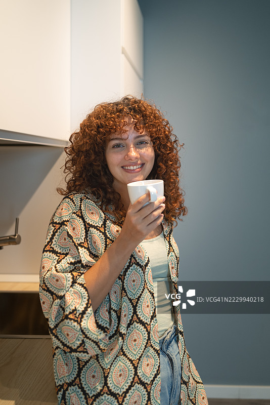 年轻女性在厨房微笑着喝咖啡图片素材