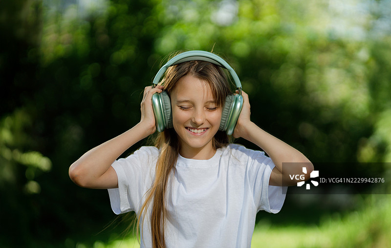 快乐的青少年在公园里戴着耳机享受音乐图片素材