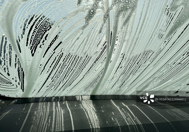 汽车挡风玻璃特写，正在用肥皂泡清洗图片素材