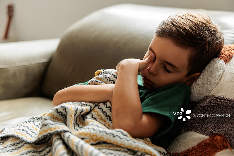 生病的男孩在家里的沙发上休息图片素材