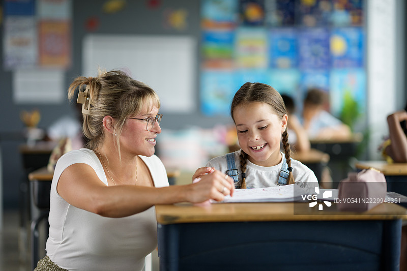 老师在色彩丰富的教室里辅导学生图片素材