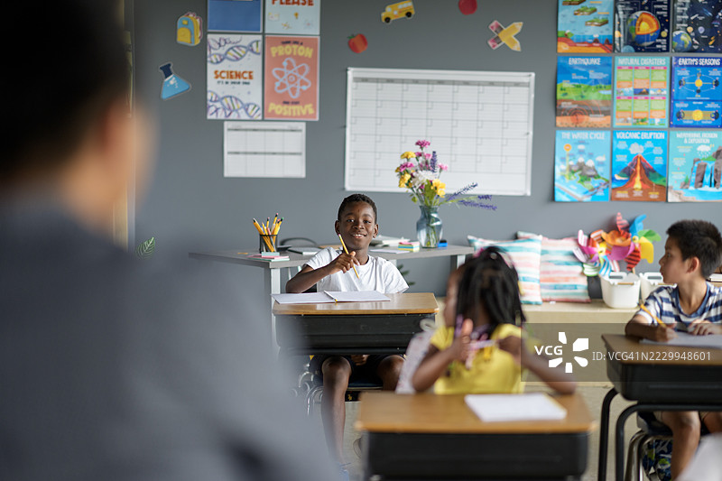 在多元化课堂环境中，学生们与教育海报和学习用品互动。图片素材