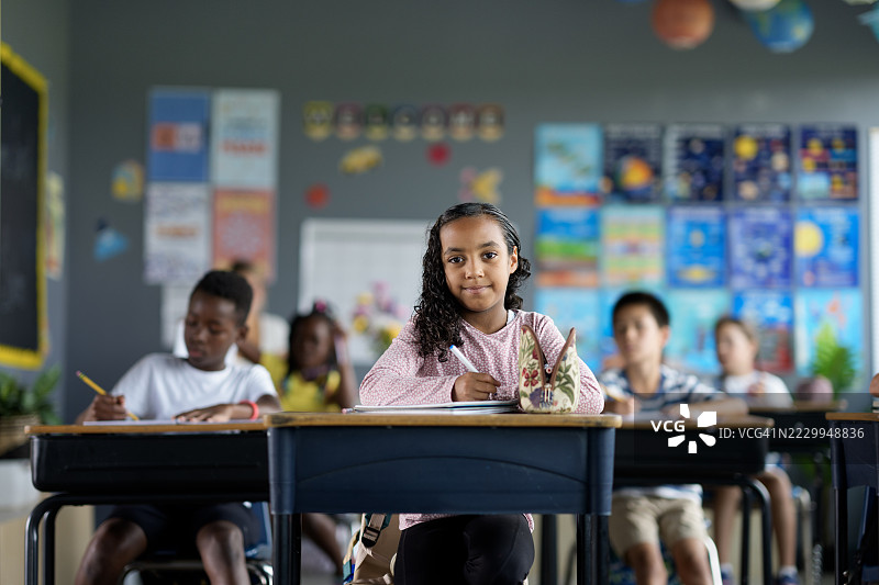 多元化的学生在明亮多彩的教室环境中专心学习图片素材