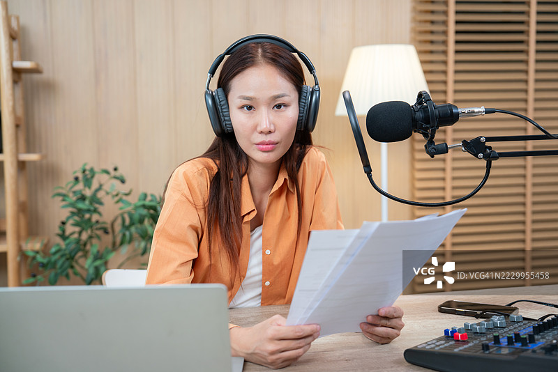 专注于录音的严肃女性播客主持人在家工作室内图片素材