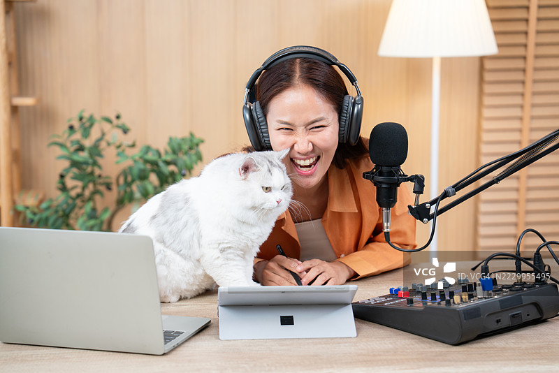 在直播录制中与猫互动的笑声播客主持人图片素材