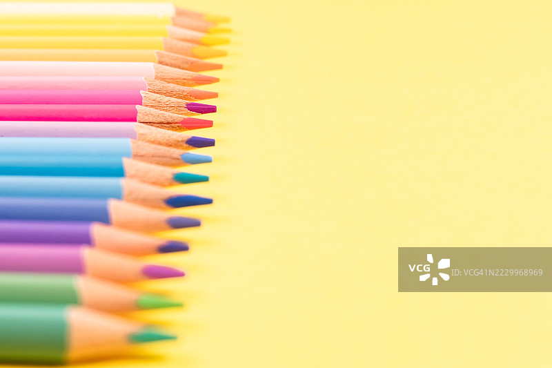五颜六色的铅笔排列在鲜艳的黄色背景上图片素材