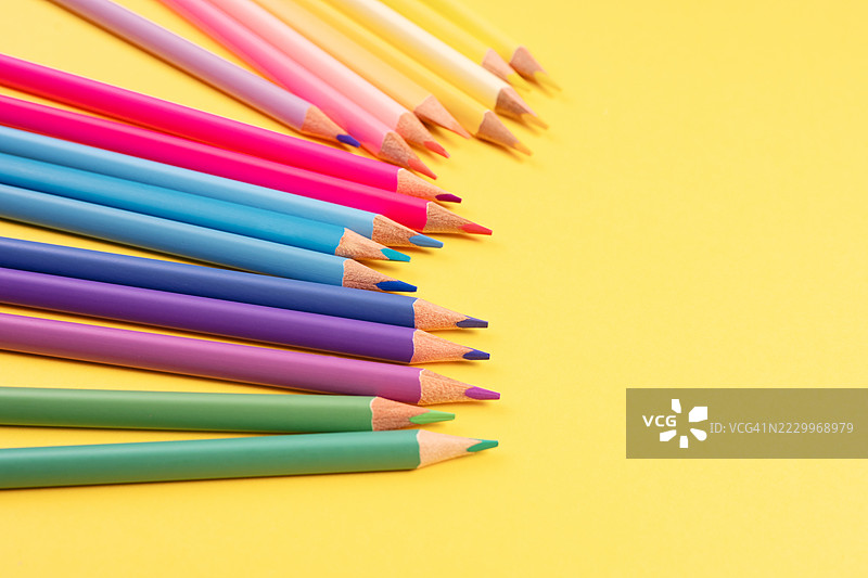 五颜六色的铅笔排列在鲜艳的黄色背景上图片素材