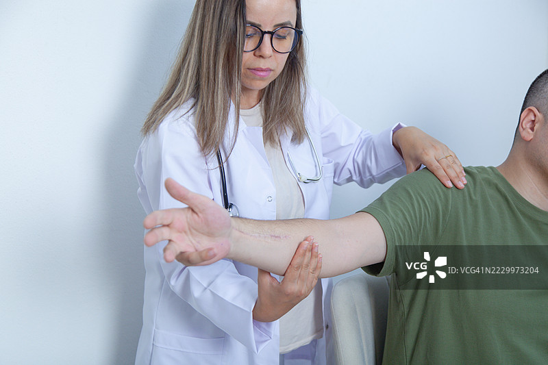 物理治疗师检查患者的肘部和肩部。图片素材