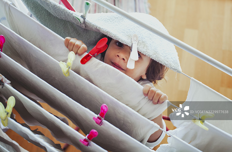 孩子在家里帮忙洗衣服时玩捉迷藏图片素材