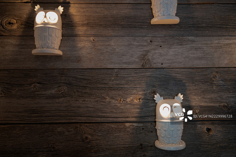 可爱的发光灯笼，带有猫头鹰设计，放在质朴的木质表面上，营造出温馨的氛围图片素材