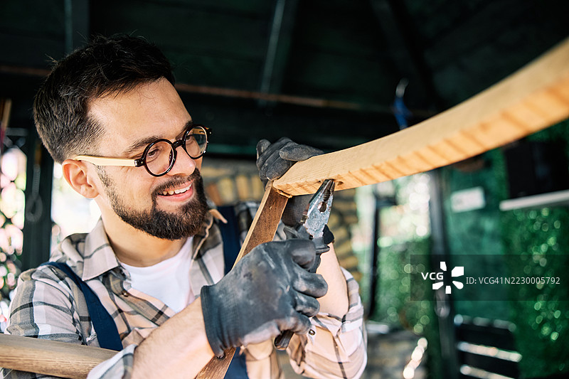 微笑的工匠在家庭工作坊中制作木工项目图片素材