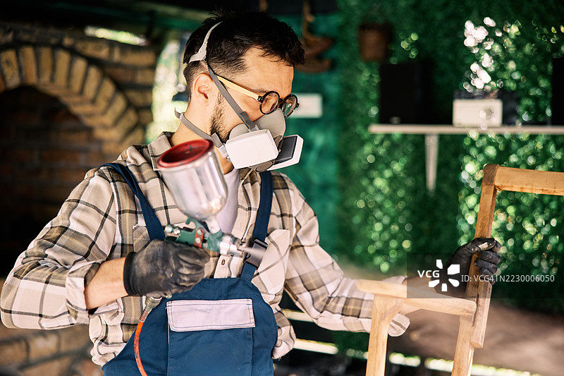 男子在工作室环境中给木家具上漆图片素材