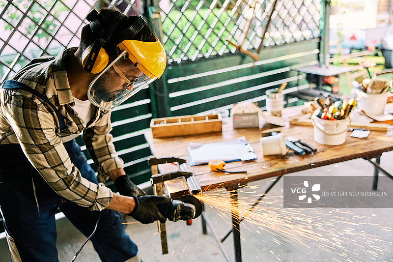 专注的工人在车间操作磨床，产生火花图片素材