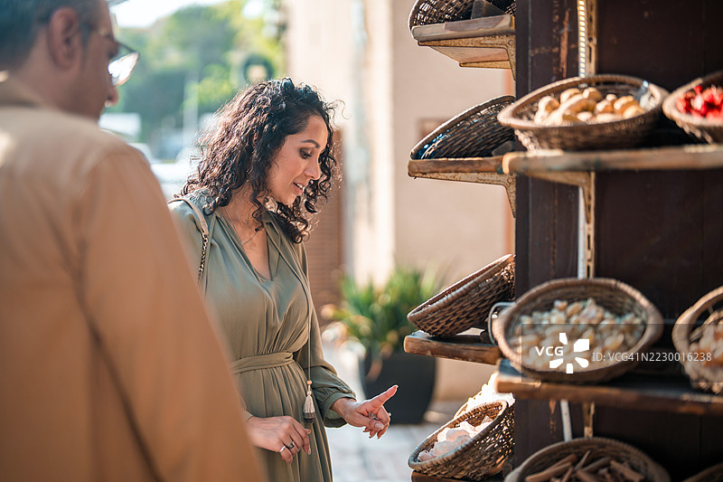 微笑的阿拉伯夫妇在阿尔法希迪阳光明媚的日子里购物香料图片素材