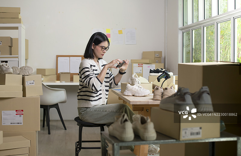 女性在线商店小企业主卖家创业者在桌子上打包邮寄包裹，准备发货。电子商务代发货服务概念。图片素材