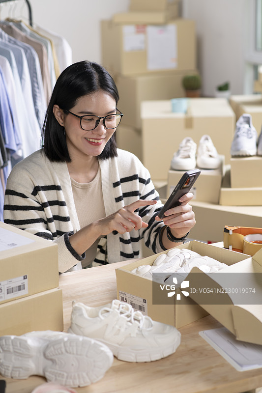 女性在线商店小企业主卖家企业家在桌子上打包邮寄包裹准备发货。电子商务代发货运输服务概念。图片素材