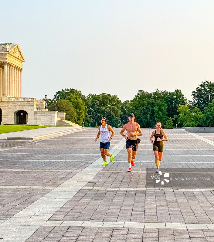 三个人在华盛顿特区的美国国会大厦附近慢跑。图片素材